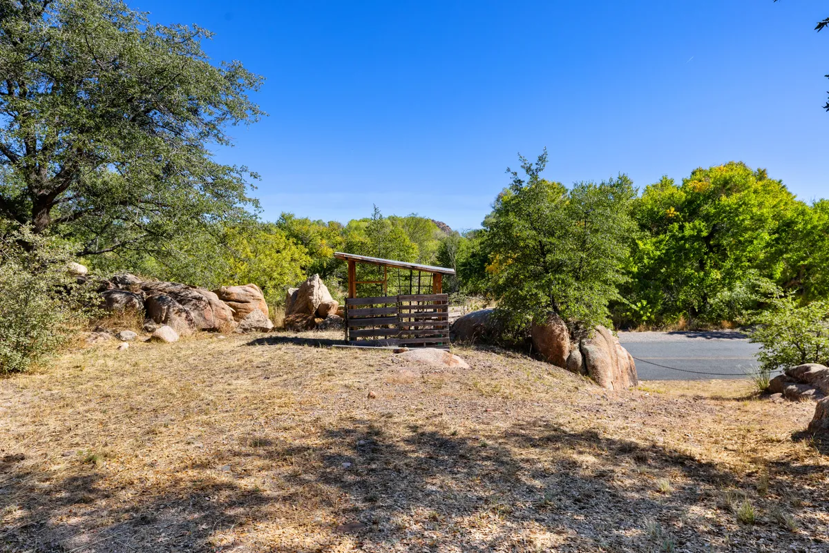 A peaceful exterior scene showcasing a wooden shelter nestled among dramatic rock formations and lush greenery. The vantage point offers a sense of immersion in nature and highlights the unique geology surrounding the bungalow.