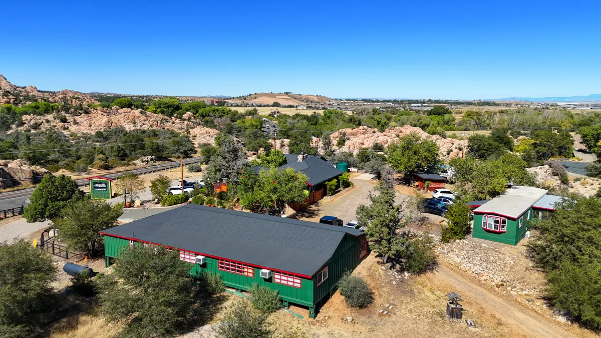 A broader exterior perspective featuring colorful buildings nestled among prominent rock formations and lush greenery. The landscape invites outdoor activities such as hiking and social gatherings, all set against a backdrop of sunset-lit rocks.